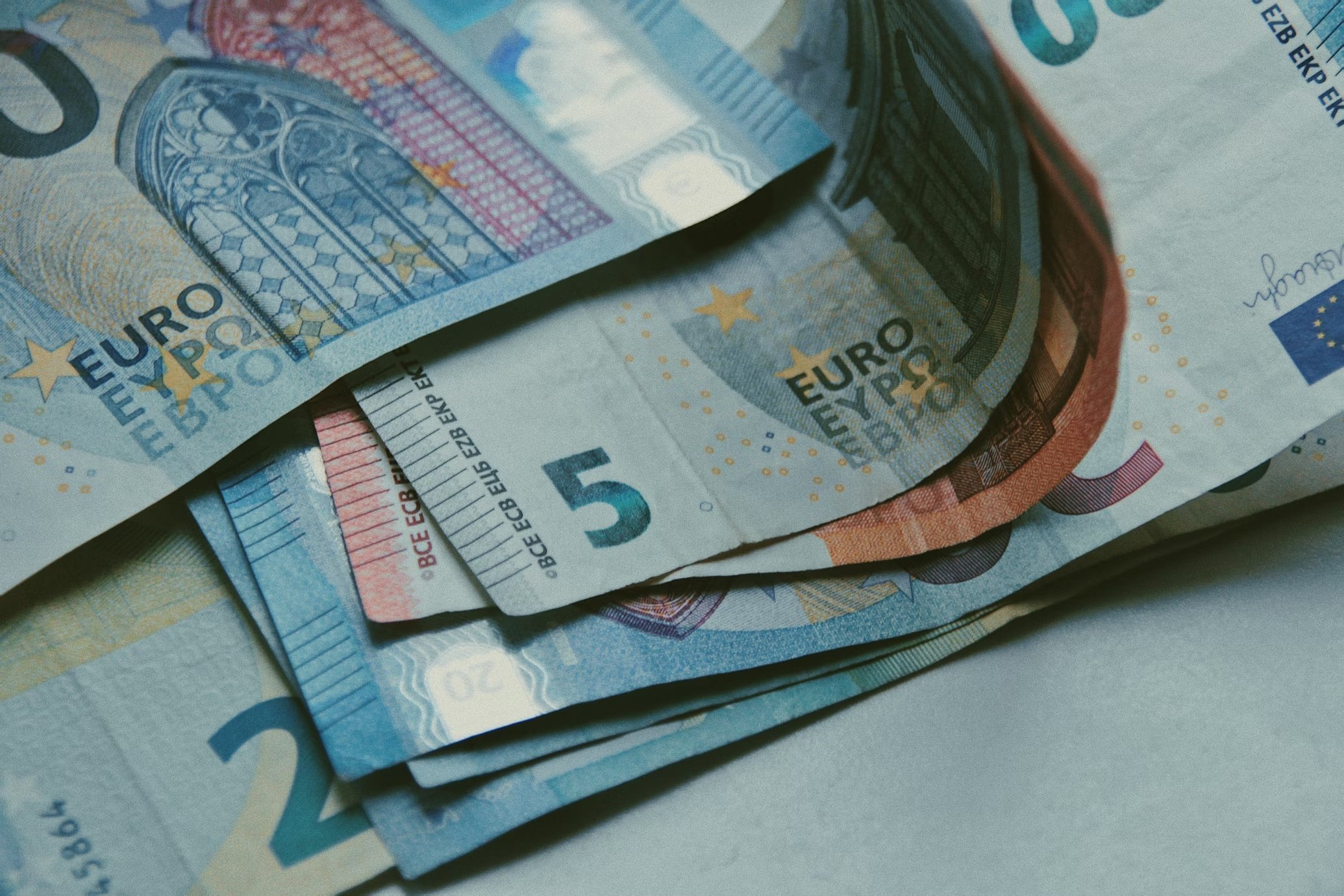 notas de euro em cima de uma mesa, com destaque para uma nota de cinco euros