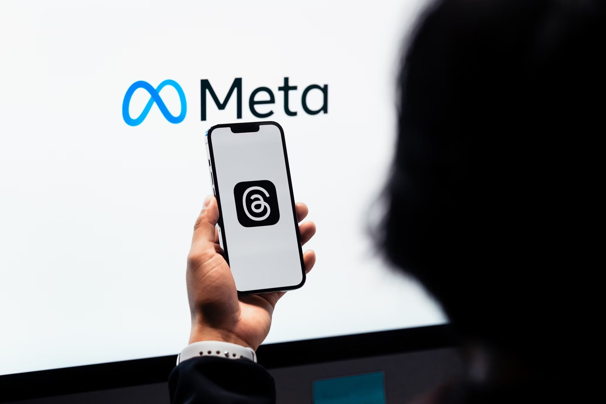 Logo da meta e pessoa a segurar smartphone com o threads