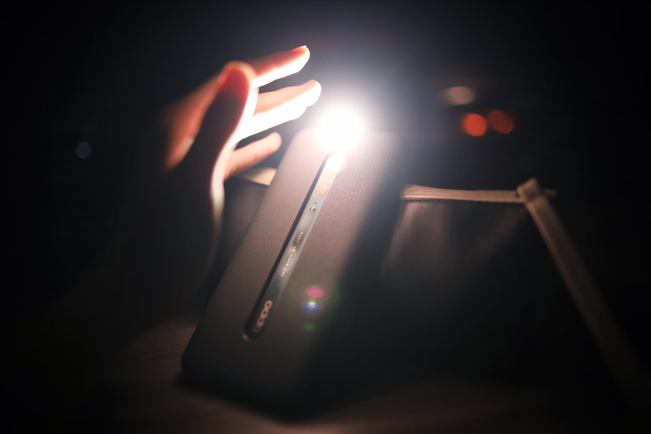 Smartphone com lanterna ligada e mão de uma pessoa