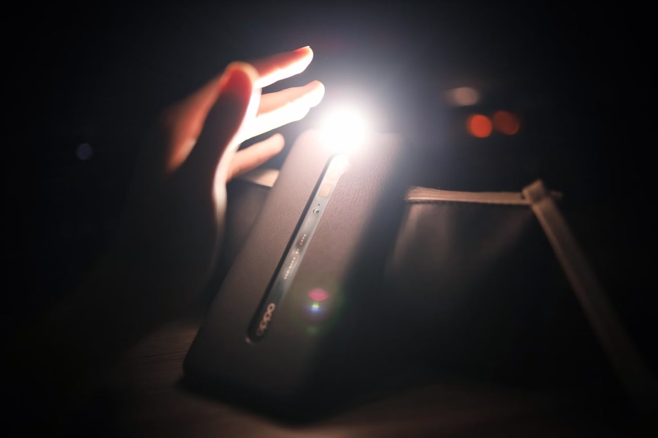 Smartphone com lanterna ligada e mão de uma pessoa