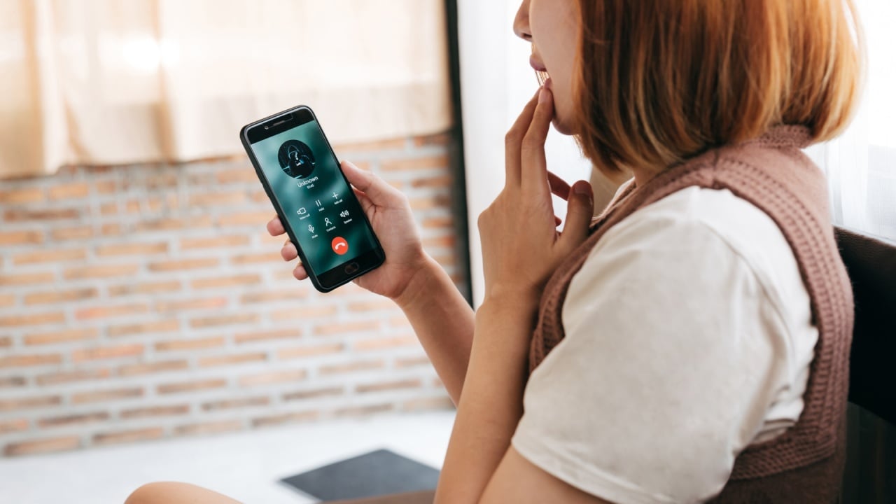 pessoa a atender telefone de um número desconhecido em esquemas