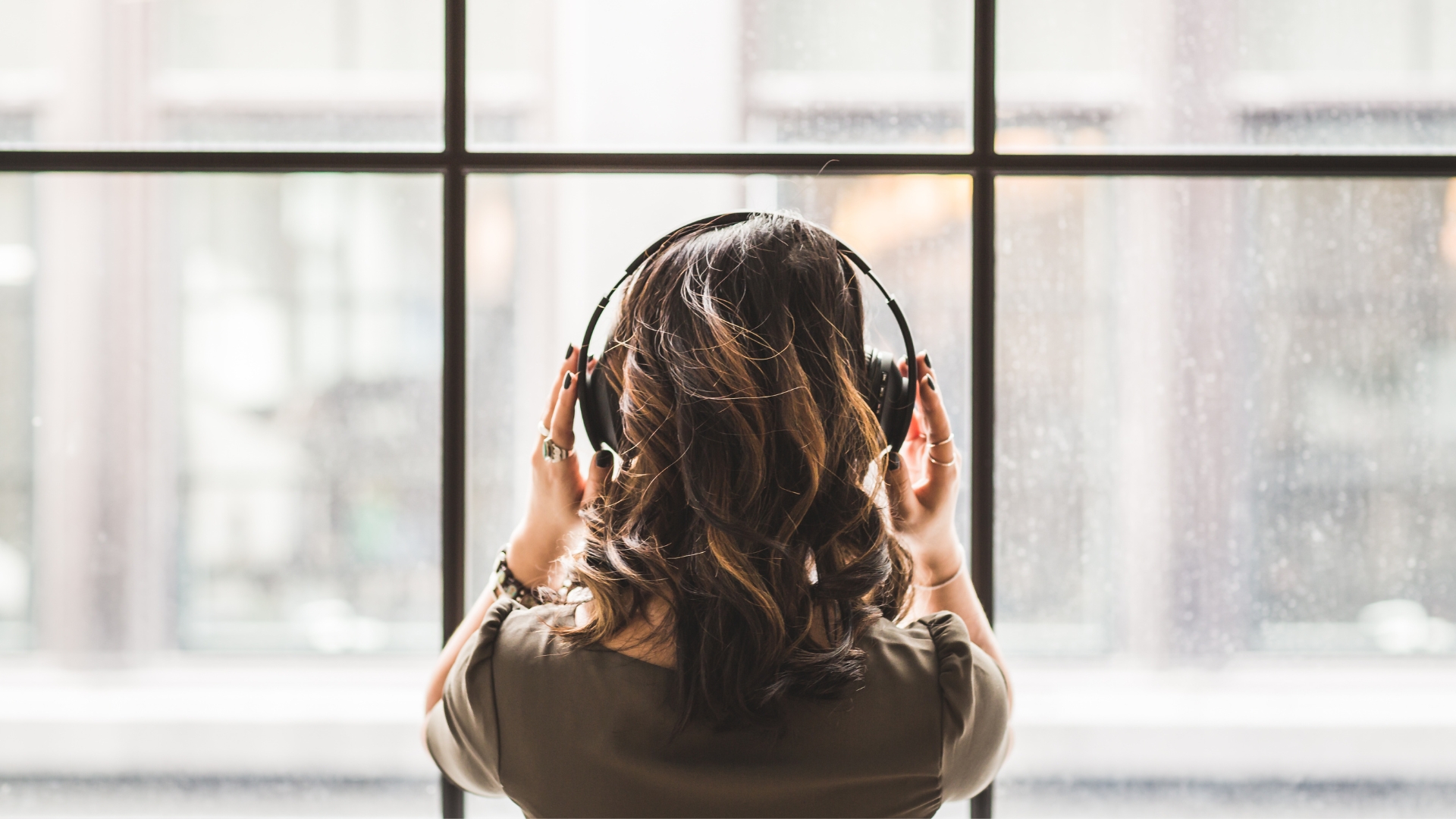 Pessoa a usar headphones em frente de uma janela