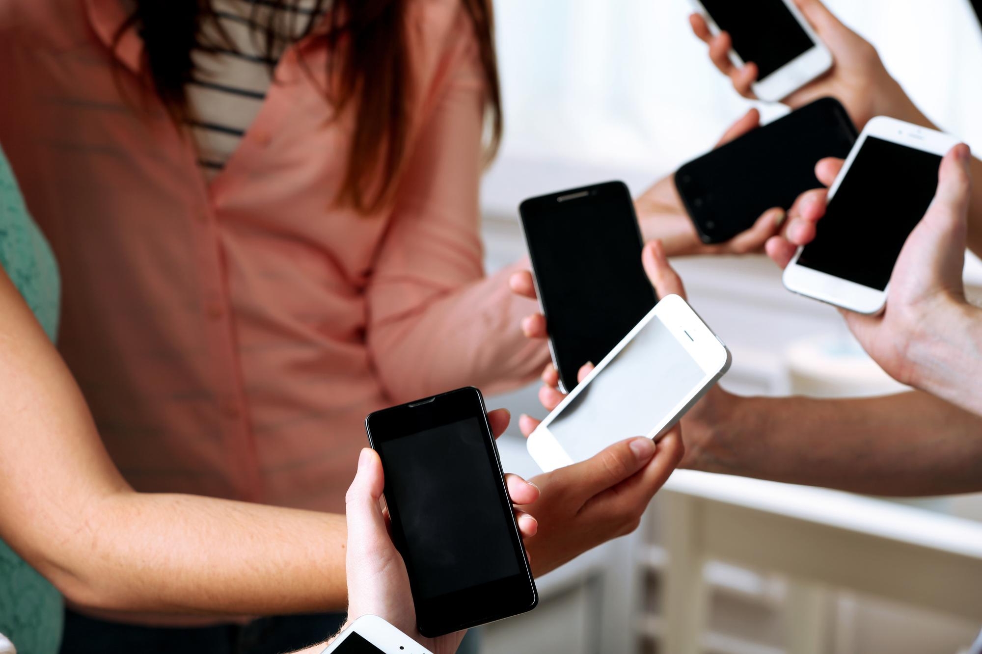 pessoas a segurarem em diferentes smartphones