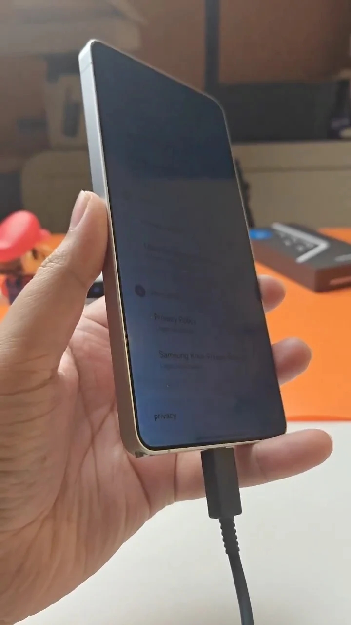 A mão segura um smartphone com a tela apontada para cima.