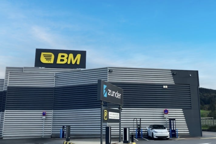 A car is parked in front of a building with a blue sign that says "Zundler".