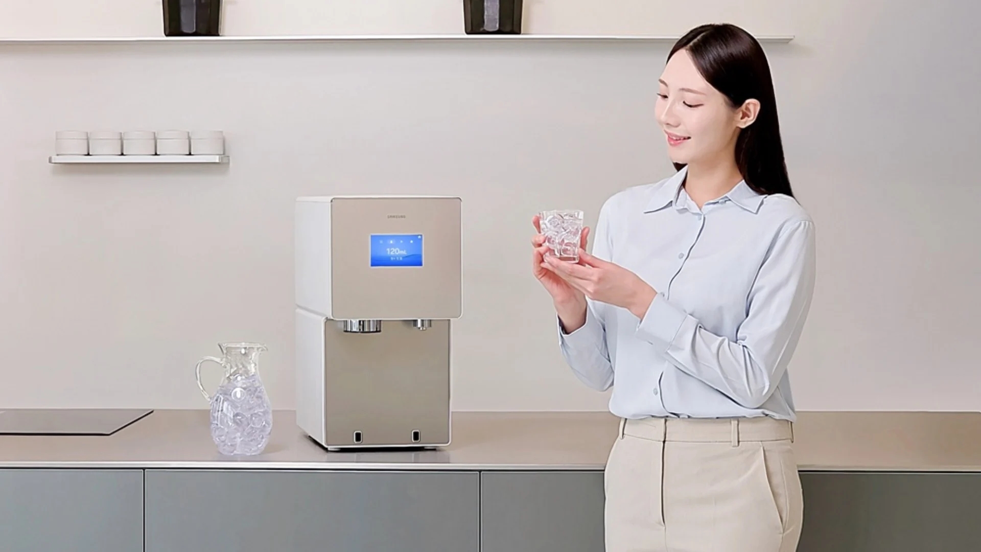 A mulher está sorrindo, segurando um copo de água.