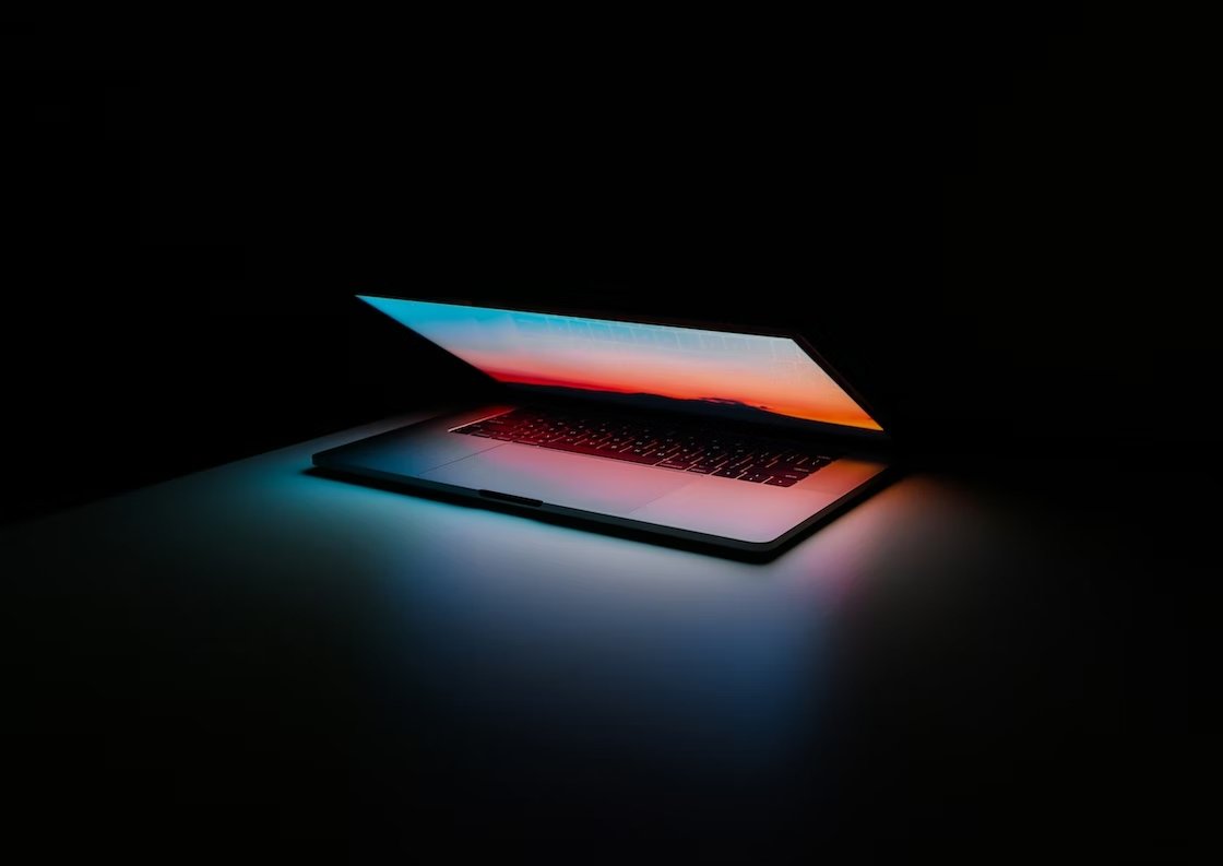 Apple MacBook sobre mesa com luz do ecrã ligada