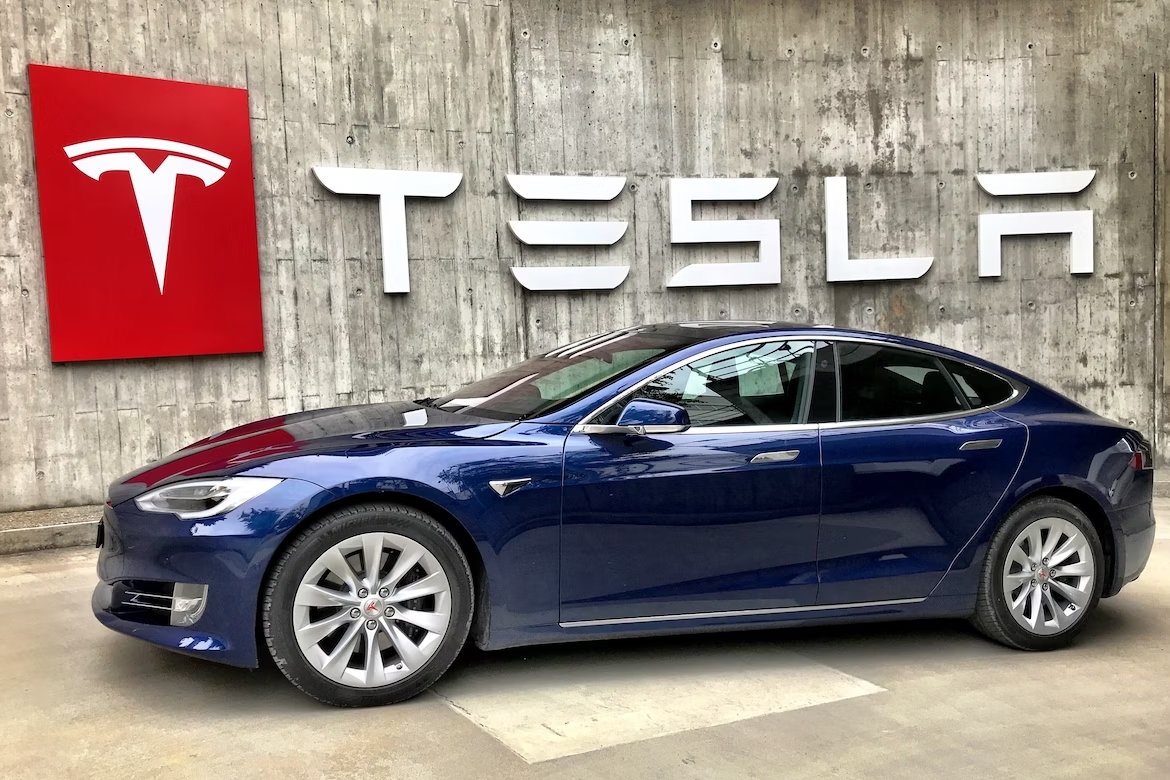 Veiculo da Tesla em frente de placa com logo da empresa