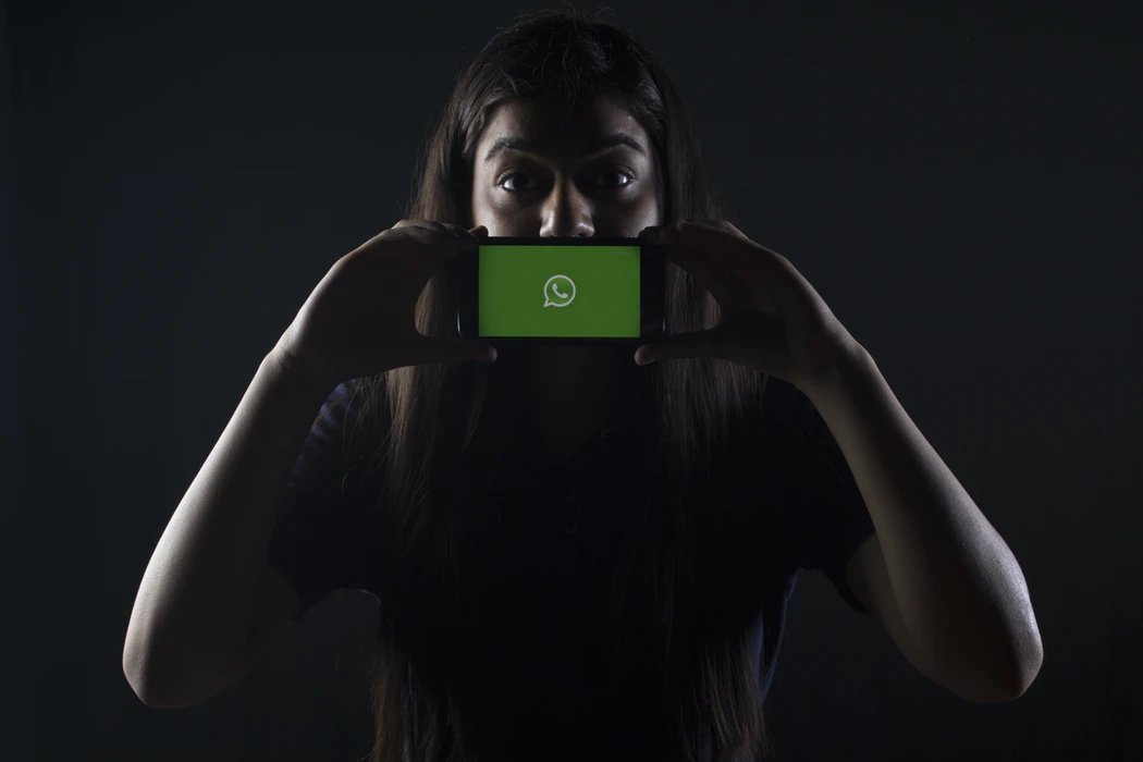 WhatsApp num smartphone sobre a face de uma utilizadora