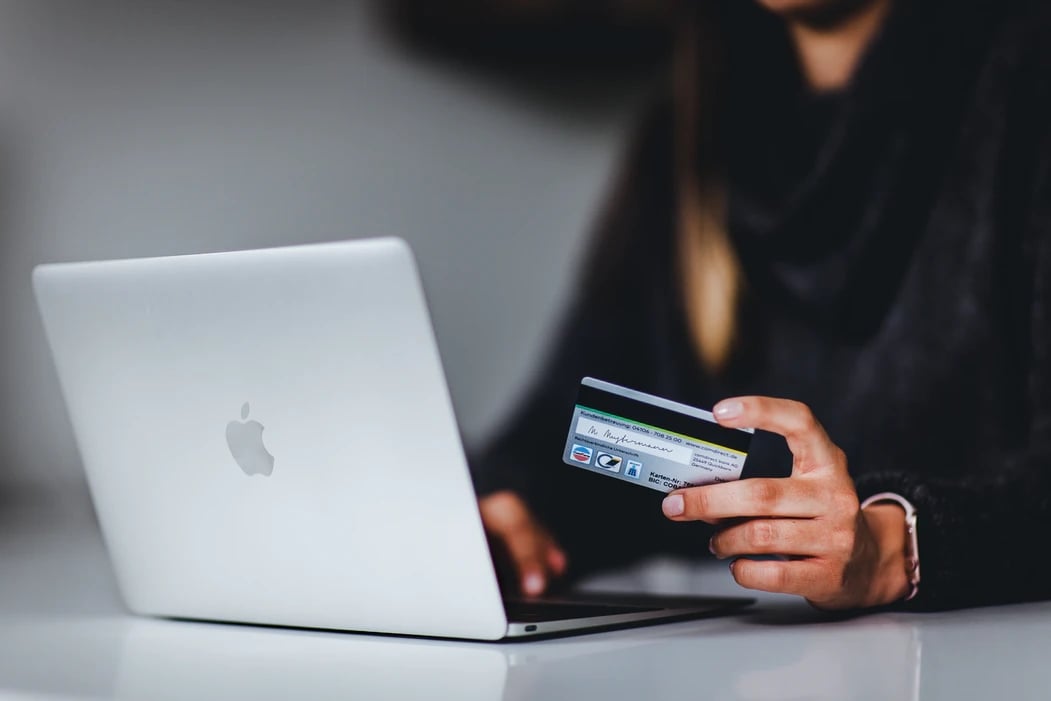 Pessoa a comprar pelo computador com o cartão de crédito